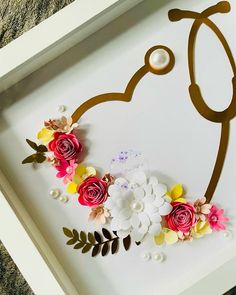 a white frame with flowers and a stethoscope in the shape of a heart