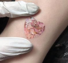 a heart shaped piece of glass sitting on top of a woman's thigh