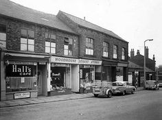 an old black and white photo of cars parked in front of stores