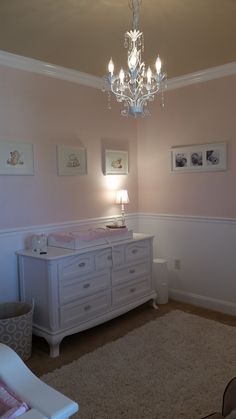 a baby's room with a chandelier, dresser and crib in it