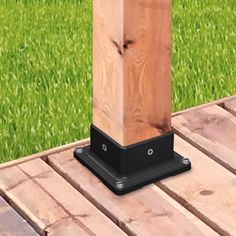 a wooden post on the ground in front of some green grass and wood planks