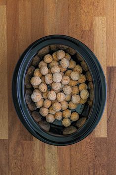 a black bowl filled with food on top of a wooden floor