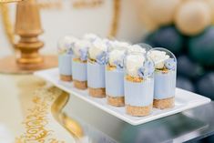 small desserts are arranged on a white plate with blue flowers and gold trim around them