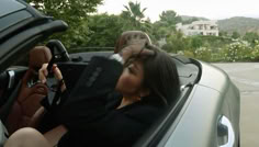 a woman sitting in the driver's seat of a car talking on her cell phone