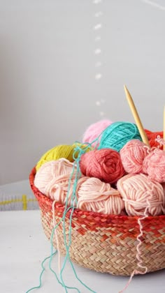 a basket filled with yarn and knitting needles on top of a white table next to a pair of scissors