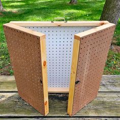 an open wooden box sitting on top of a wooden table next to a green field