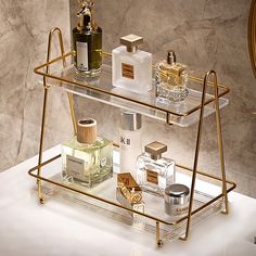 three tiered glass shelf with bottles and perfumes on it