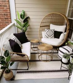 two wicker chairs sitting on top of a porch next to a potted plant