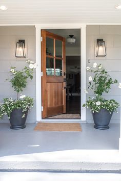 two large planters with white flowers are on the front porch