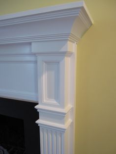 a white fireplace mantel in a room with yellow walls