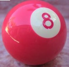 a red pool ball with the number eight on it's side, sitting on a gray surface