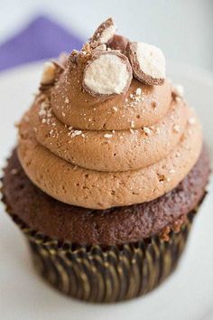 a cupcake with chocolate frosting and marshmallows on top is sitting on a plate