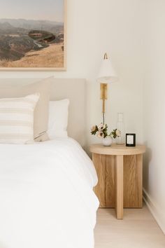 a white bed sitting next to a wooden night stand