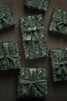 six wrapped presents with green bows and flowers on them, all tied up in different patterns