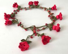 a close up of a bracelet with red flowers on the side and green leaves attached to it