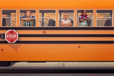 three children standing in front of a school bus with their arms crossed and looking out the window