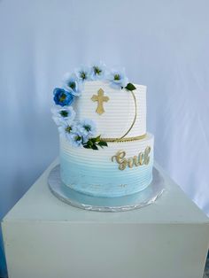 a white cake with blue flowers and a cross on top