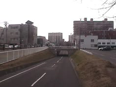 an empty street with cars driving on it and buildings in the background, as seen from a distance