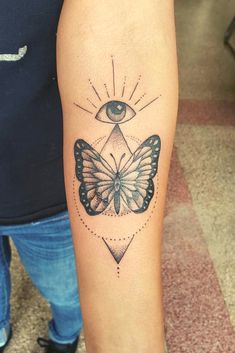 a woman's arm with a butterfly tattoo on it and an all seeing eye