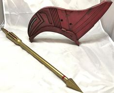 an odd shaped object with a long metal handle and gold colored arrow on it's side