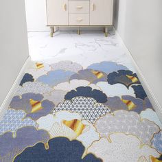 a blue and yellow rug with clouds on it in front of a white dresser next to a cabinet