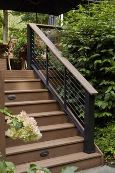 a set of stairs leading up to a deck with an umbrella over it and flowers in the background