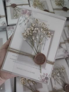 a person holding a card with flowers on it in front of many other greeting cards