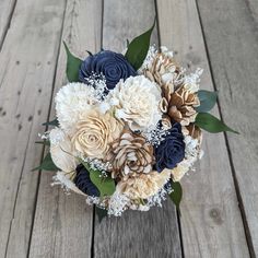 a bridal bouquet with blue and white flowers sits on a wooden surface, ready to be used as a wedding bouquet