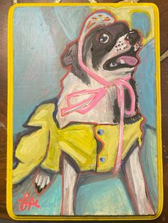 a painting of a dog wearing a yellow jacket and pink scarf on a wooden table