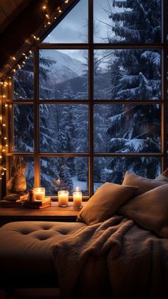 candles are lit on the window sill in front of a snowy mountain view at night