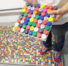 a man holding a multicolored object on top of a colorful tile floor in front of a window