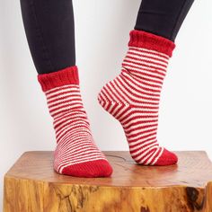 a woman wearing red and white striped socks on top of a wooden block with her feet up