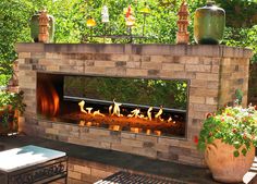 an outdoor fireplace with lit logs and potted plants