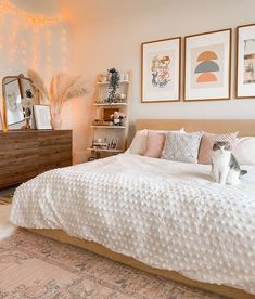 a white cat sitting on top of a bed in a bedroom next to a dresser