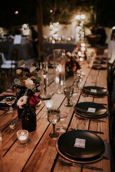 an outdoor table set for dinner with candles and plates