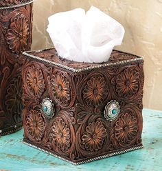 two brown leather tissue boxes sitting on top of a blue wooden table next to each other