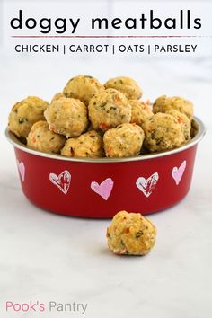 a red bowl filled with chicken meatballs on top of a white table next to two small hearts