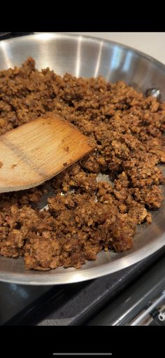 a wooden spoon in a metal pan filled with food