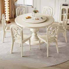 a white dining table and chairs in a room with beige carpeted flooring next to a window