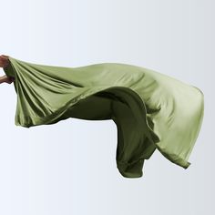 a woman flying through the air while holding onto a green cloth over her head,