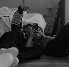 a man and woman laying on the floor with their cell phones in hand, taking pictures