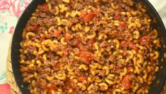 a skillet filled with pasta and ground beef in sauce on top of a table