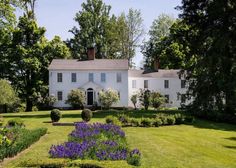 a large white house surrounded by trees and flowers