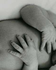 a black and white photo of a baby's hand on the belly of its mother