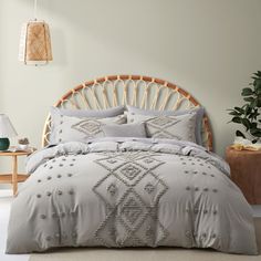 the bed is made with grey linens and pillows