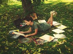 a woman laying on the grass reading a book