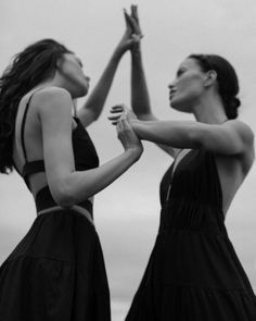 two women in black dresses holding hands together