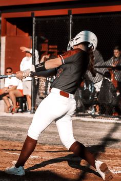 a woman swinging a baseball bat on top of a field