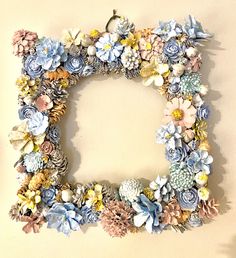 a decorative letter made out of flowers and pineconis on a wall in the shape of a wreath