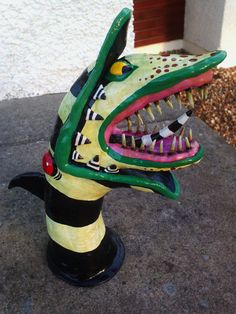 a ceramic sculpture of a dragon head with sharp teeth and fangs on it's face